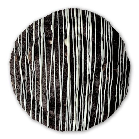 Close-up of a chocolate cookie with white chocolate drizzle and pieces of milk, dark and white chocolate poking through the surface.